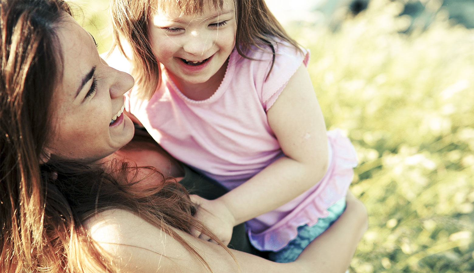 Mutter mit Kind mit Downsyndrom, lachend. 