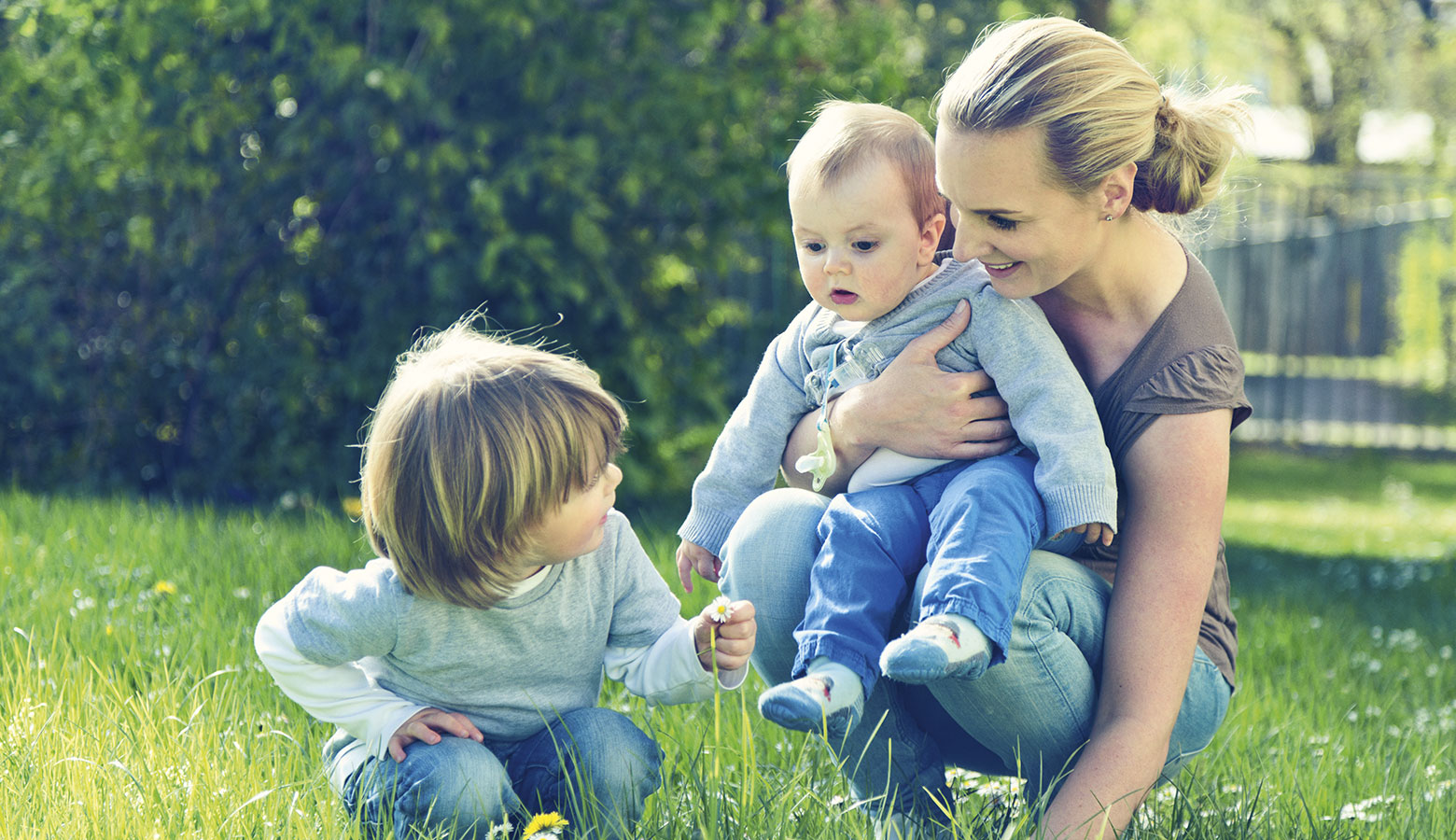 Mutter mit zwei Kleinkindern im Garten