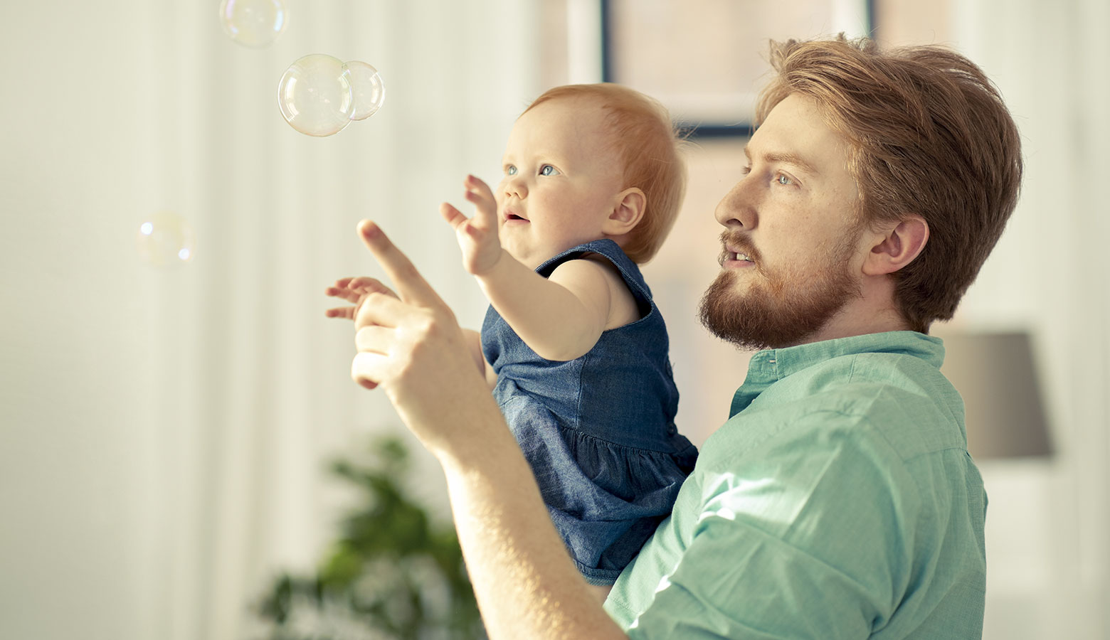 Vater mit Baby auf dem Arm, Seifenblasen betrachtend. 