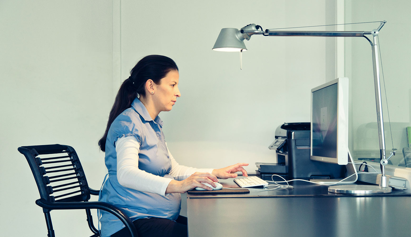 Schwangere Frau sitzt am Computer. 