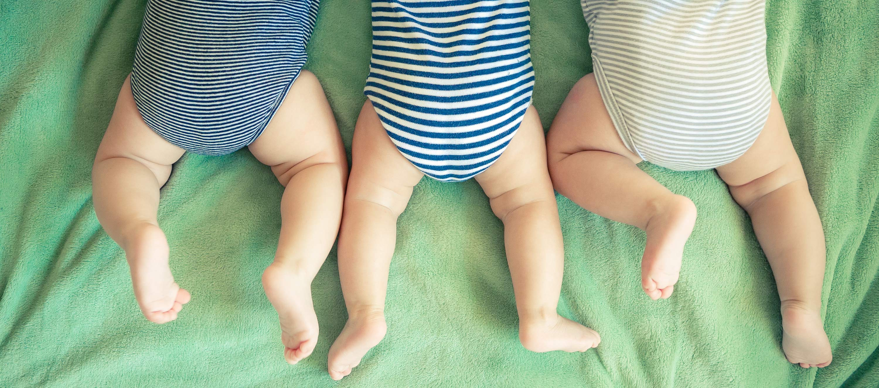 Drei Babys liegen auf dem Bauch