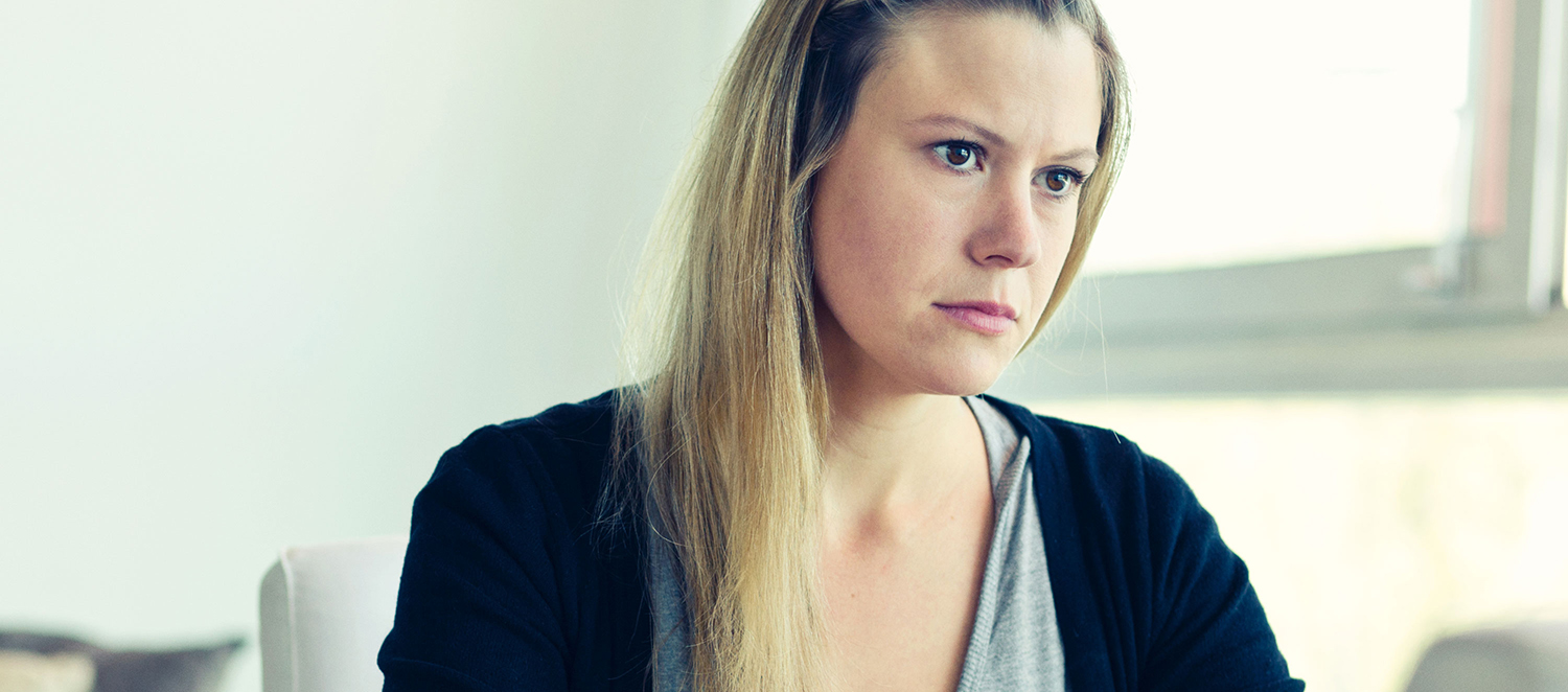 Junge Frau sitzt traurig am Tisch. 