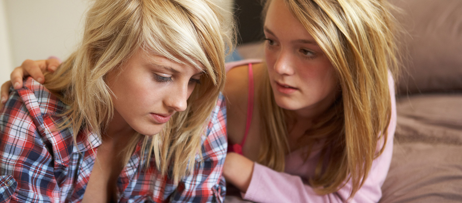 Zwei junge Mädchen mit besorgten Gesichtern im Gespräch. 