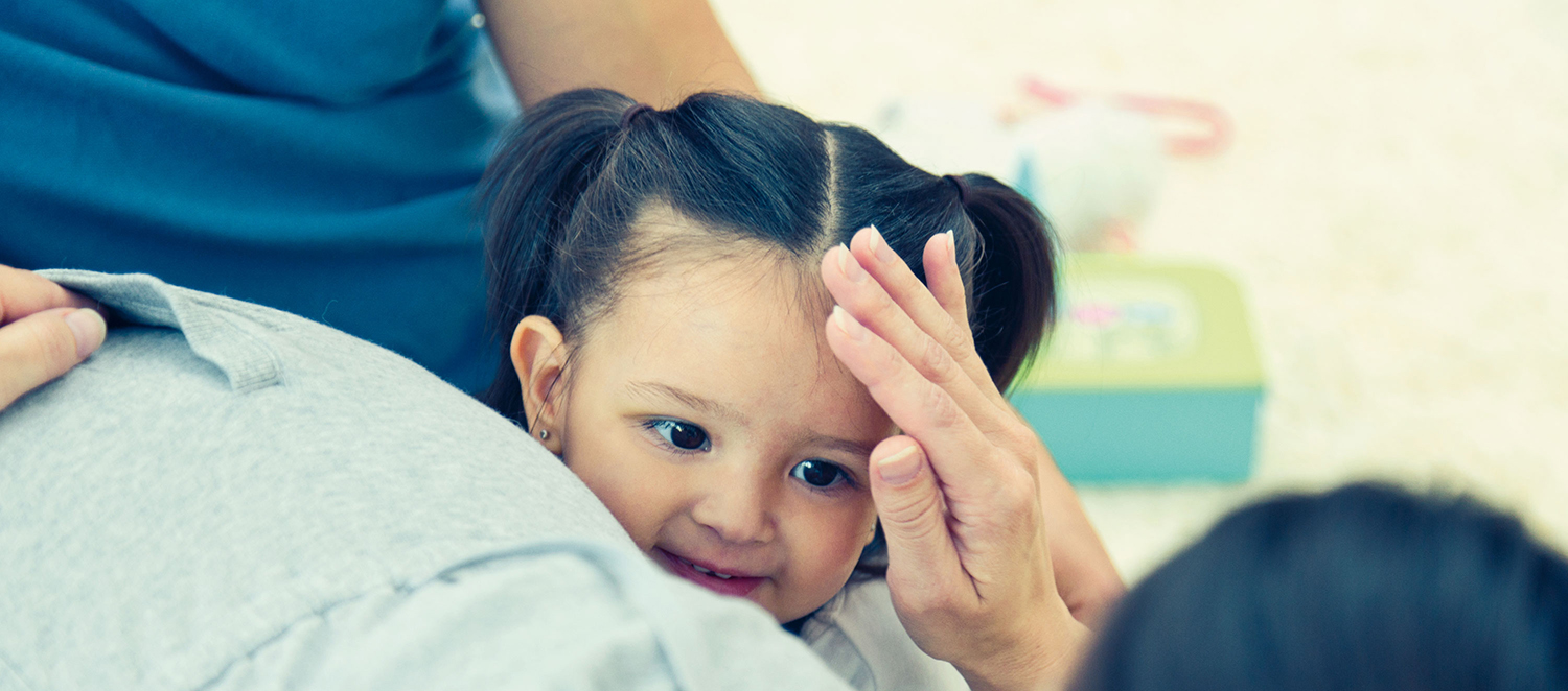 Mutter streichelt kleine Tochter am Kopf. 