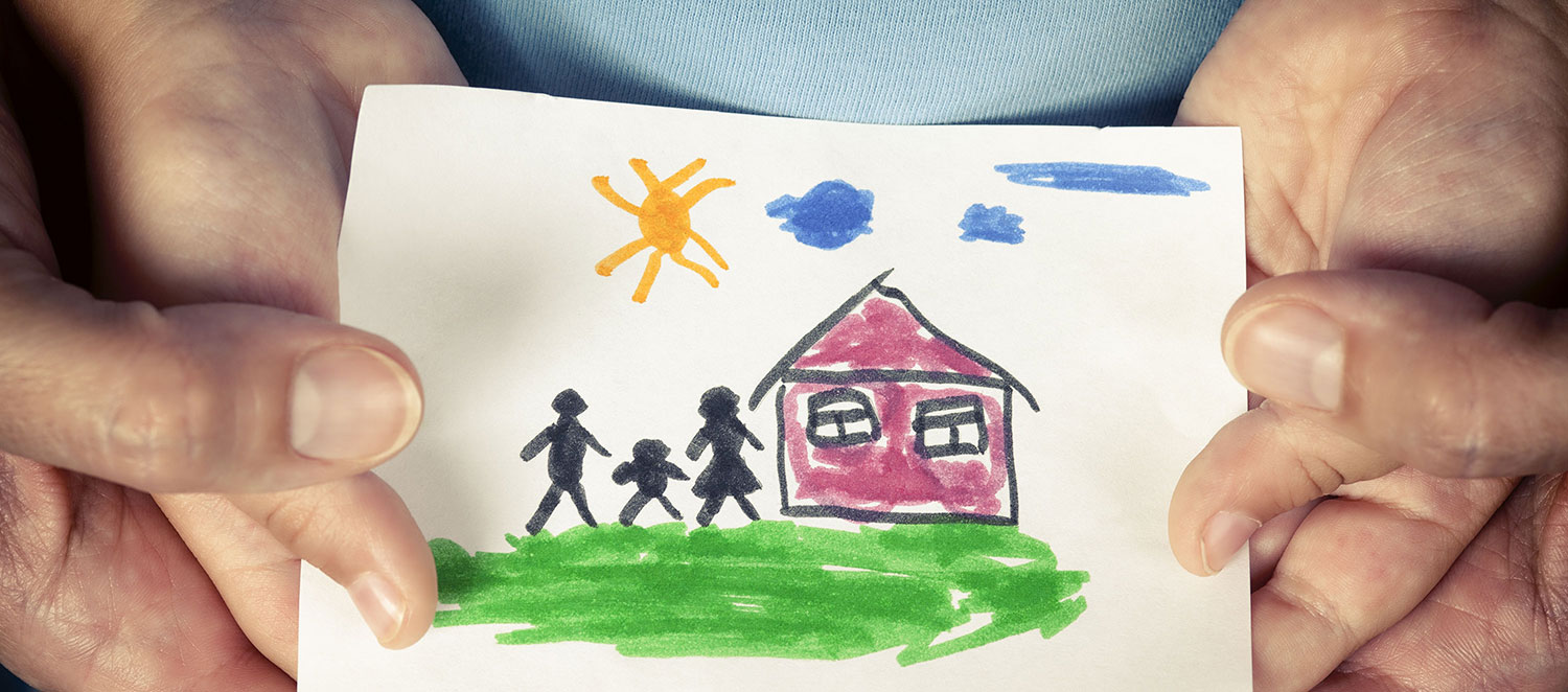 Hände halten ein gemaltes Kinderbild von einem Haus mit einer Familie. 