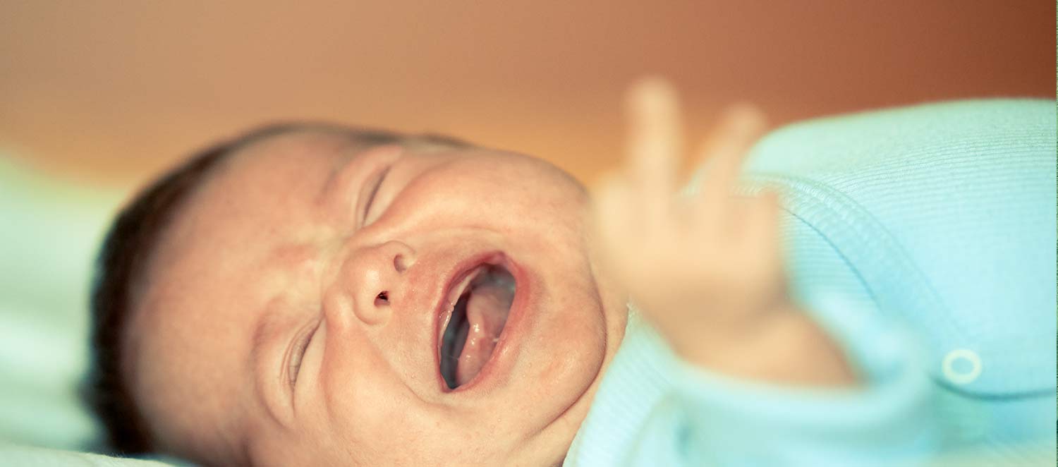 Schreiendes Baby liegt im Bett. 