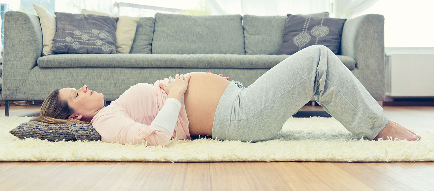 Schwangere Frau liegt auf dem Teppich. 