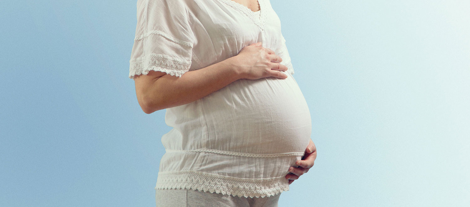 Schwangere streicht über ihren Bauch. 