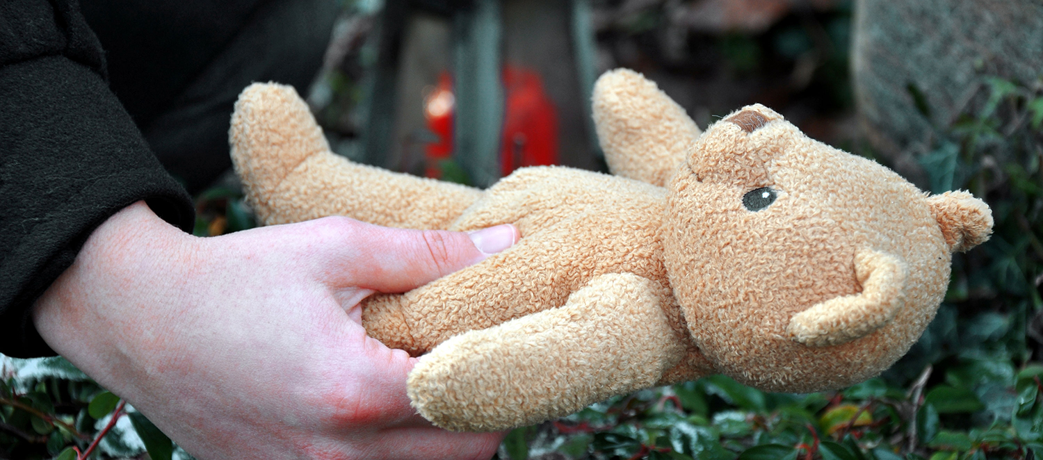 Eine Hand hält einen Teddy fest.