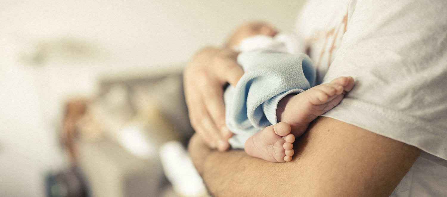 Vater hält Baby auf dem Arm. 