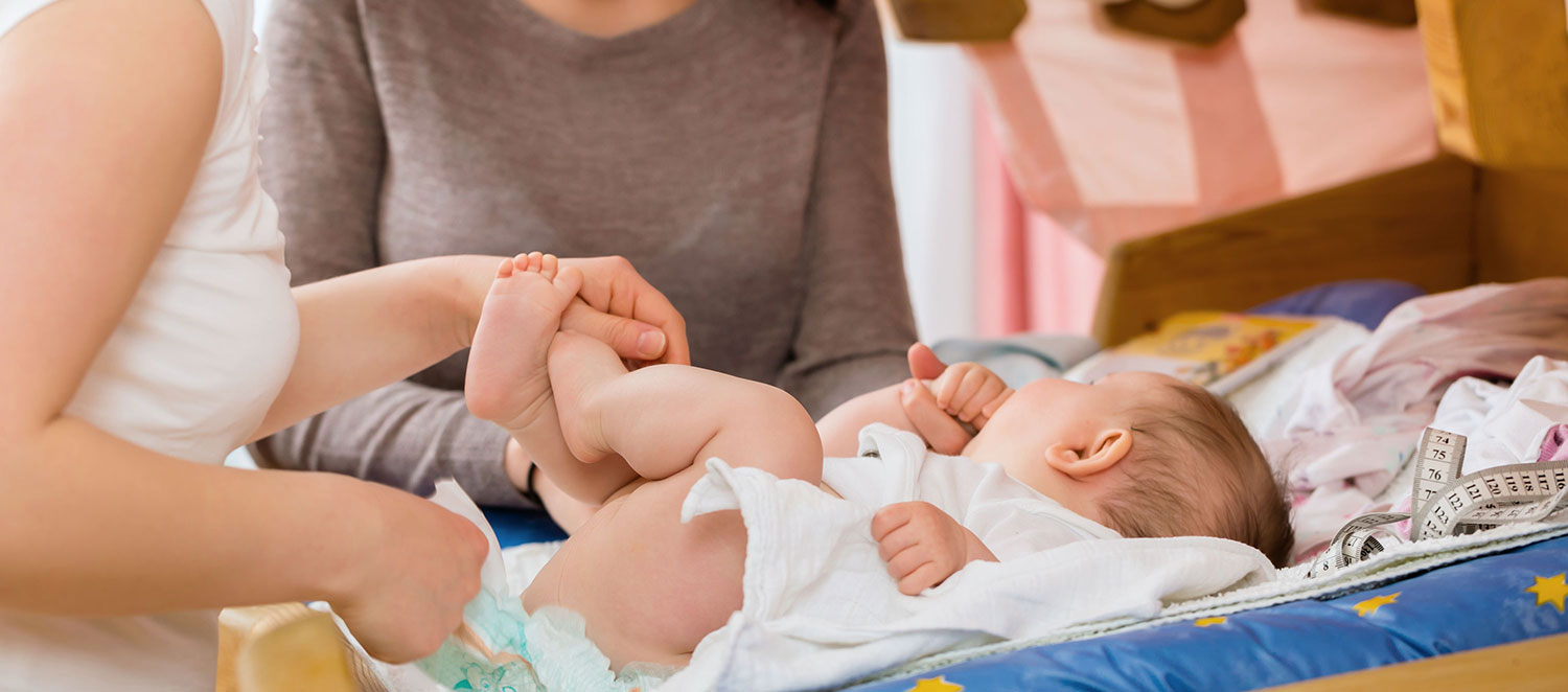 Hebamme und Mutter beim Wickeln eines Babys. 