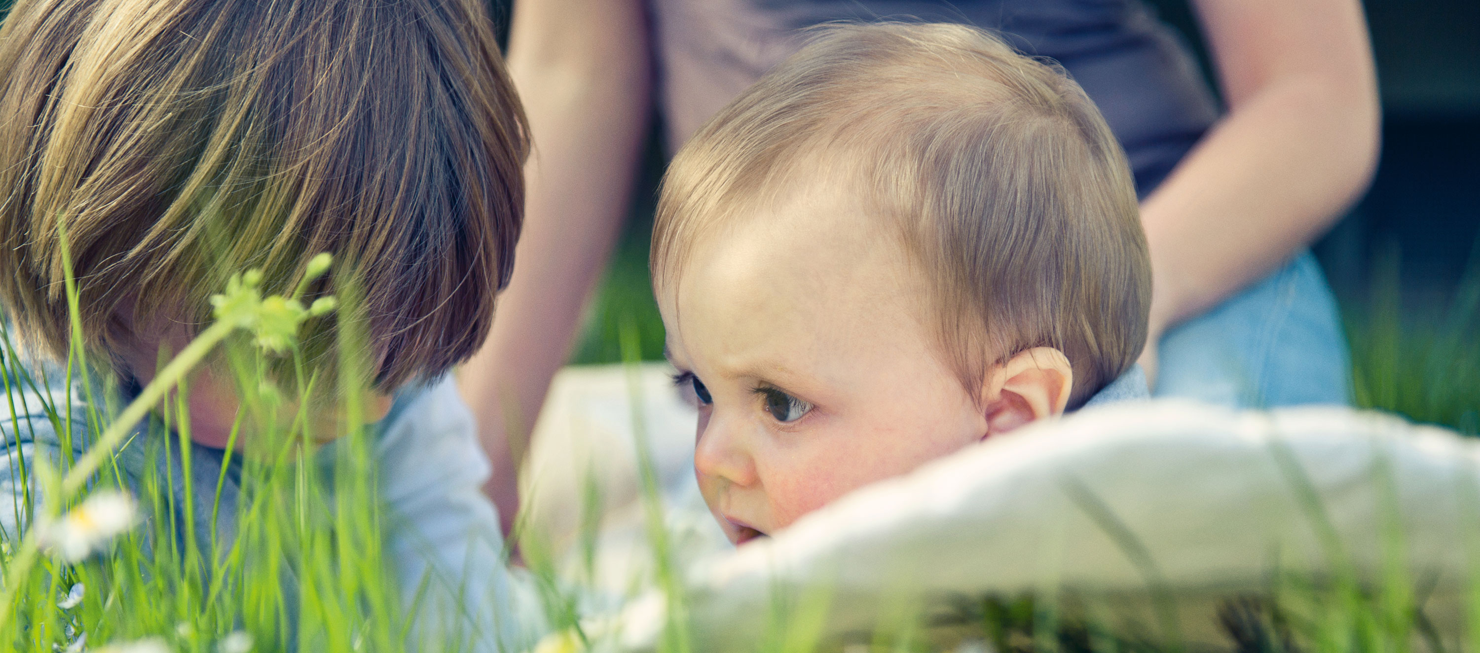 Mutter mit zwei Kleinkindern auf der Wiese. 