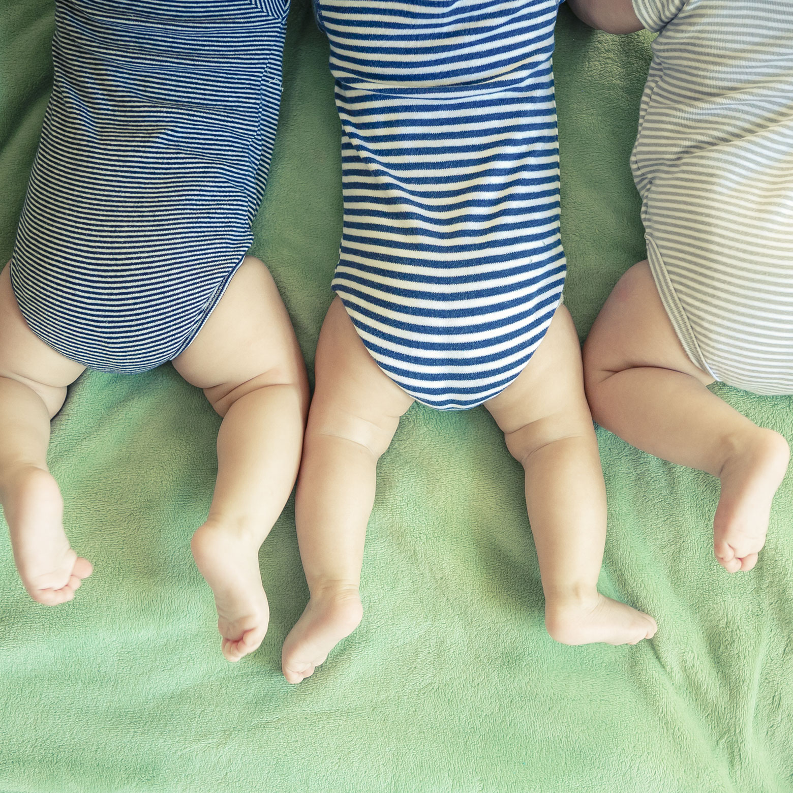 Drei Babys liegen auf dem Bauch