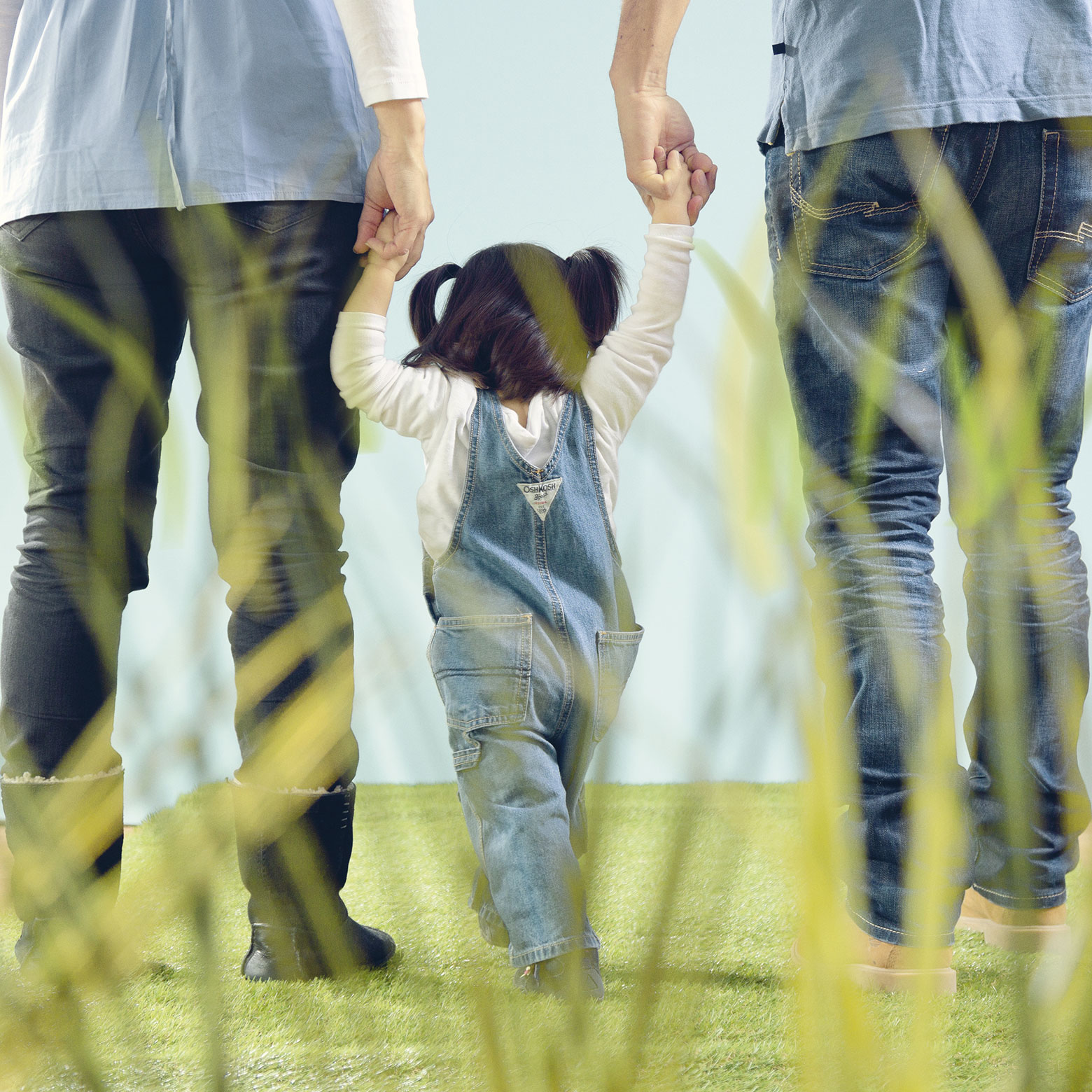 Mutter und Vater fassen ihr Kleinkind an den Händen