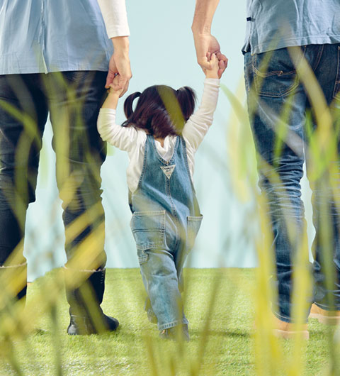 Kleines Mädchen an der Hand von zwei Erwachsenen. 