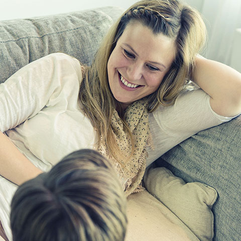 Lachende Frau auf dem Sofa im Gespräch. 