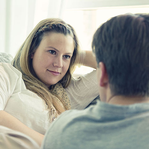 Frau auf dem Sofa im Gespräch mit einem Mann. 