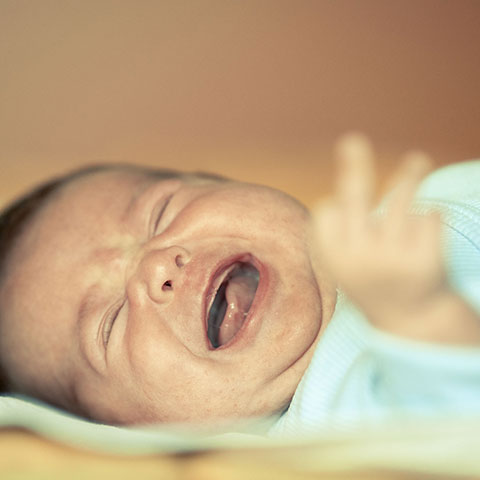 Schreiendes Baby liegt im Bett. 